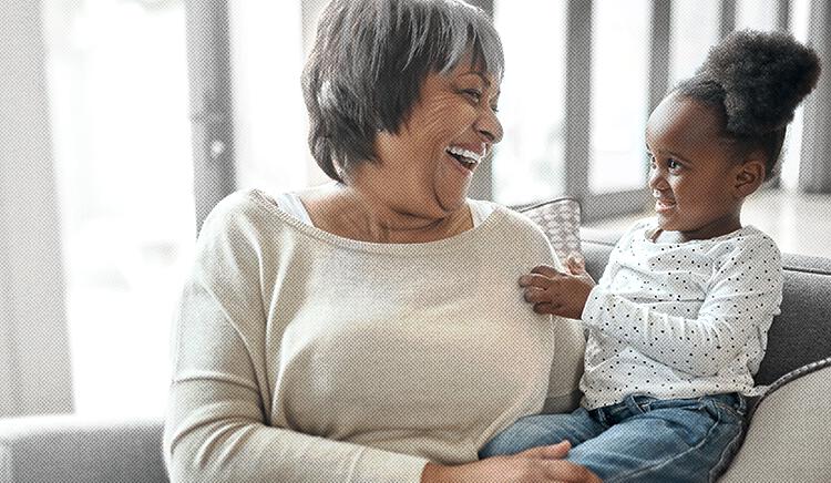 Older woman laughing with little girl smiling sitting on her lap